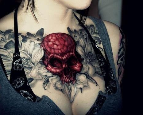 Very red skull that stands out on this tattoo with a background of shadow flowers, all tattooed on the chest of this girl