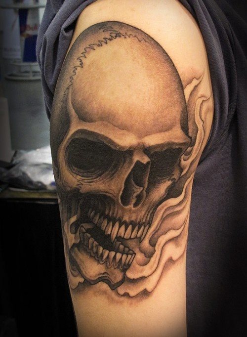 A simple skull with large fangs tattooed on the arm