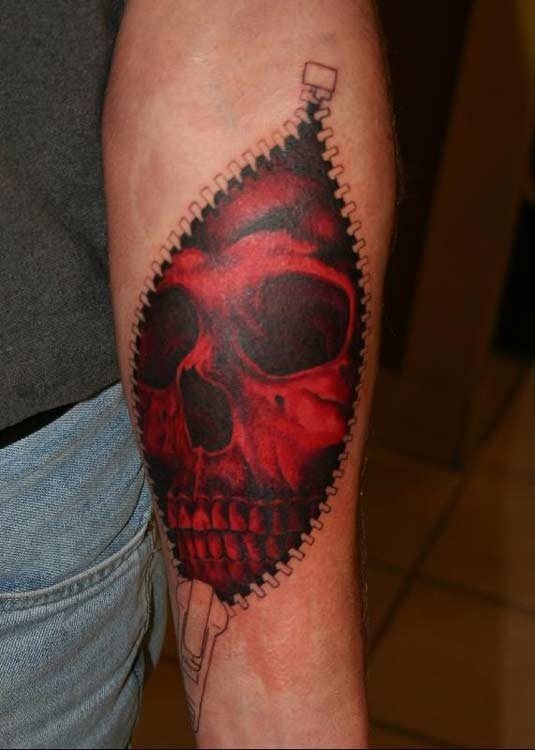 Tatuaje de una cremallera que se encuentra abierta como si la propia piel tuviese una cremallera y en cuyo interiro se puede apreciar una calavera roja con sombreados y brillos en negro