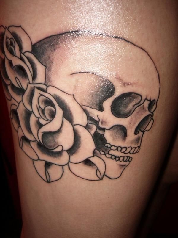 Tatuaje de calavera rodeada de flores, que está inacabada y que si se atreve con colores fuertes y vivos le va a quedar un resultado muy interesante porque ya de por sí se ve que el trabajo del tatuador está siendo bastante bueno