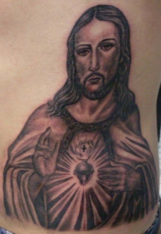 Tatuaje del Sagrado Corazón de Jesús realizado exclusivamente a color negro y con gran trabajo del sombreado para realizar un gran trabajo en el gesto y facciones de la cara y el cuello, un bonito tatuaje el que tenemos delante