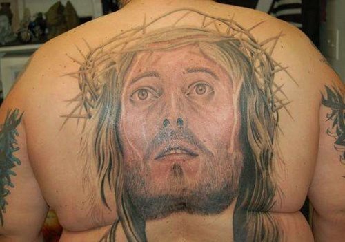 Tattoo on the back of a great countenance of the face of Jesus Christ looking at the sky, as you can see the tattoo is not yet finished or that seems to us and has been filled with a soft reddish color all over the face