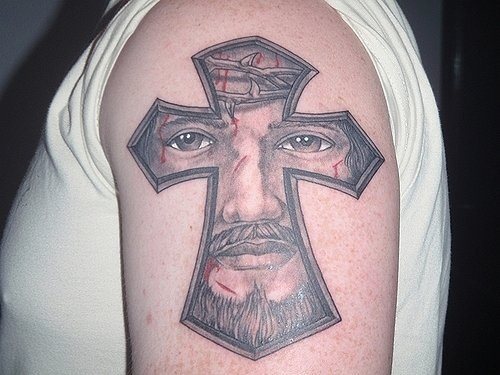 Tattoo of a cross that has been drawn inside the face of giggle with the beards and the crown of thorns, a very unique tattoo by joining two key parts of the Christian, the cross and the face of the Lord