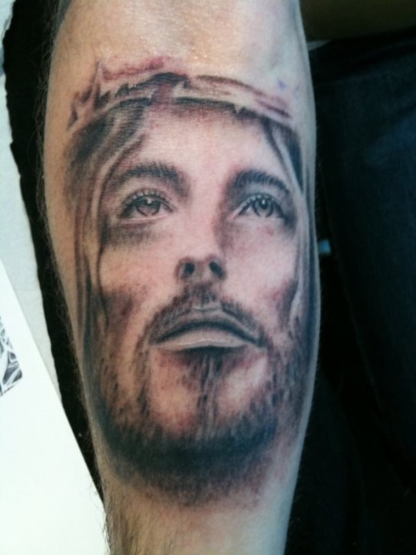 Tatuaje del rostro de Jesucristo realizado en la pierna y del que destacamos el gran realismo conseguido al jugar con unas sombras muy bien realizadas por parte del tatuador y unos ojos en los que el brillo conseguido es su rasgo más característico