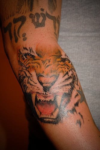 The enraged face of a tiger tattooed on the forearm