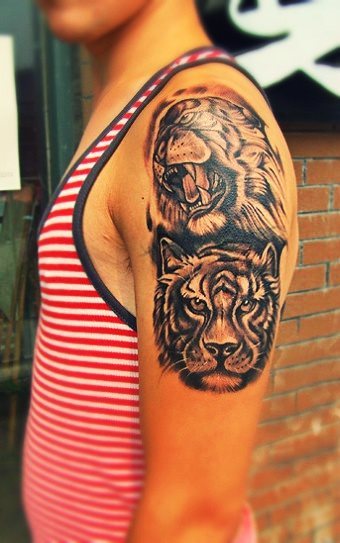 Two fierce tiger heads tattooed on this boy's arm